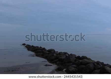Tranquil seascape with Stone pier and cloudy sky.
