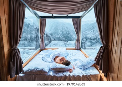 Tranquil Serene Calm Woman Sleeping On A Soft White Cozy Comfortable Warm Bed In Room With Snowy Winter Mountains View