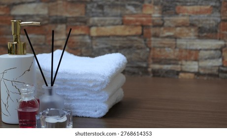 A tranquil spa arrangement featuring white orchid flowers, stacked white towels, lit candles, smooth stones, and bamboo accents on a wooden mat.