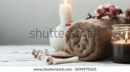 A tranquil spa setting featuring lit candles, soft flowers, and a plush towel, evoking a sense of calm and rejuvenation.