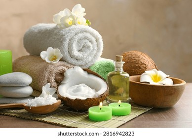 A tranquil spa setup featuring rolled towels stones aromatic oils candles and fresh flowers arranged on a bamboo mat