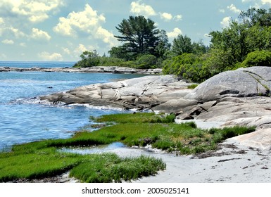 Tranquil summer scene in coastal Maine. View of small sand beach and huge granite boulders along rugged shoreline of Clark Island in mid-coast Maine.