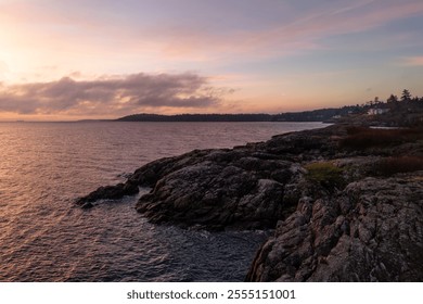 A tranquil sunrise casts warm hues over the rocky coastline of Victoria, Vancouver Island, BC, Canada, creating a peaceful and picturesque scene. Perfect for nature and landscape enthusiasts. - Powered by Shutterstock