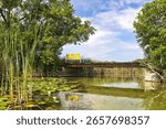 Tranquil view of three empty yellow chairs on a small bridge above the Bark River on a sunny Summer day near Summit, Wisconsin.