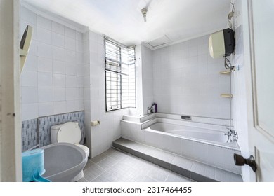 A tranquil white bathroom featuring a bathtub, toilet, and washbasin. A minimalist bathroom adorned with a bathtub, toilet, and sink. - Shutterstock ID 2317464455