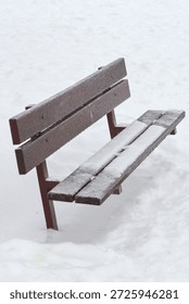 A tranquil winter scene featuring an empty wooden bench with snow accumulation in a serene public park, evoking calm and cold weather.