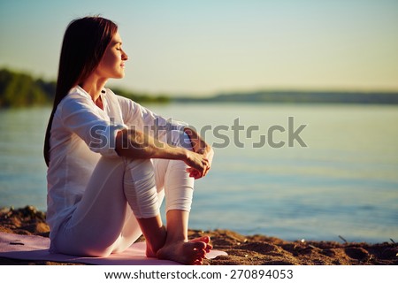 Tranquil young woman sitting on the beach