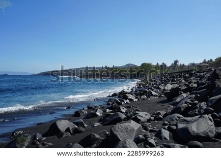 Tranquility at Jasri Beach, Karangasem, Bali, Indonesia, rocky beach with big black stones, blue sea and sky as background, tranquil and looks beautiful.