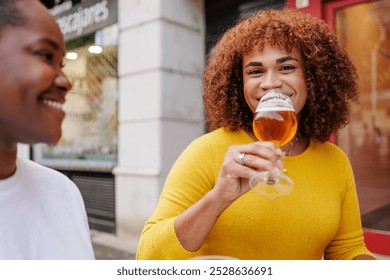 Trans woman drinking a craft beer with her friend and smiling to the camera. - Powered by Shutterstock