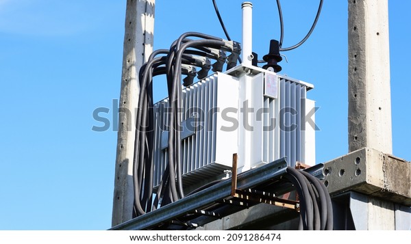 Transformer on concrete\
column beam . Oil type three phase transformer with high voltage\
cable on turquoise sky background with copy space. Closeup and\
focus on the\
subject.
