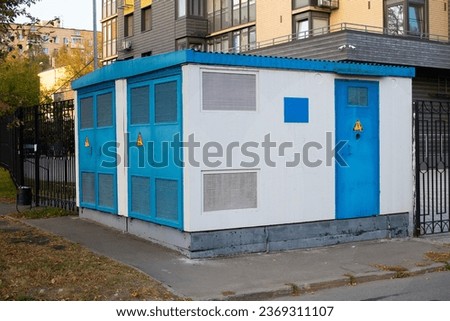 Transformer for a residential building. in summer. white with blue doors.