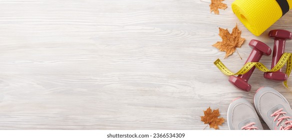 Transforming your physique in fall. Top view composition of cozy shoes, tape measure, dumbbells, karemat, autumn leaves on light wooden background with marketing space - Shutterstock ID 2366534309