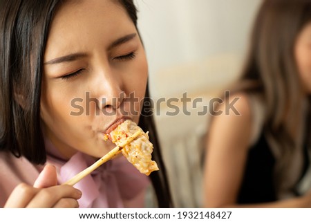 Transgender Asian Woman eats Chili spicy Wonton and hanging to mouth with sweat delicious enjoy eating, copy space blur background