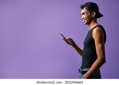 Transgender Smiling Male With Mobile In Hand Side View On Purple Background Portrait