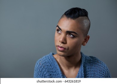 Transgender woman looking away while standing against gray background