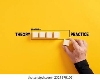 Transition of theory into practice. Implementation of theories in practice. Hand places a wooden cube to the loading bar with the words theory and practice. - Shutterstock ID 2329398103