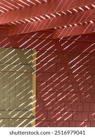 Transitory pattern of afternoon sunlight slanting across roof elements, gate, and shingled siding on exterior of a beach house in mid October on the Gulf Coast of Florida