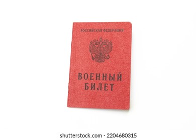 Translation: RUSSIAN FEDERATION. Military ID Book. Military ID book of a serviceman of the Russian Federation isolated on a white background. Red paper soldier's card in close-up view. Mobilization 