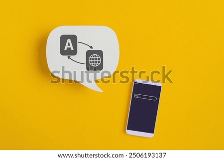 For translator application, foreign languages concept, top view of real white speech bubble paper with translation symbol and smartphone on yellow background