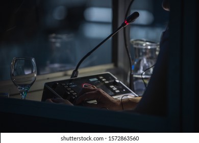 Translator Or Translation Booth At A Conference. Hand Of A Person For Simultaneous Translating Is Seen Working In A Booth. Glass Of Water Next To A Translator.