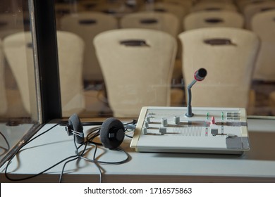 translators cubicle . interpreting - Microphone and switchboard in an simultaneous interpreter booth . Soft focus of wireless Conference microphones and notebook in a meeting room.
