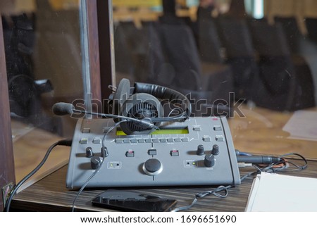 translators cubicle . interpreting - Microphone and switchboard in an simultaneous interpreter booth . Soft focus of wireless Conference microphones and notebook in a meeting room.