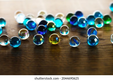 Translucent Glass Marbles On A Wold Wooden Desk. Shallow Depth Of Field.