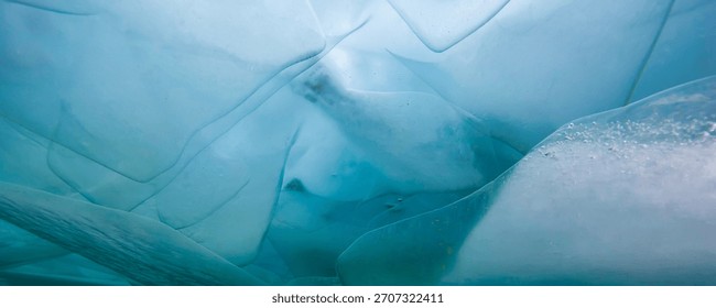 Translucent ice layers and formations appear above, with a turquoise hue, on the surface of frozen Lake Baikal. Sunlight filters through in winter.