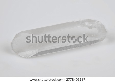 Translucent quartz prism with natural facets showcased. Photograph of pure quartz crystal with internal structures highlighted on neutral background for educational purposes