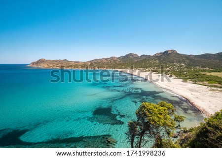 Translucent turquoise Mediterranean sea lapping onto an almost deserted Ostriconi beach in the Balagne region of Corsica with the Desert des Agriates behind