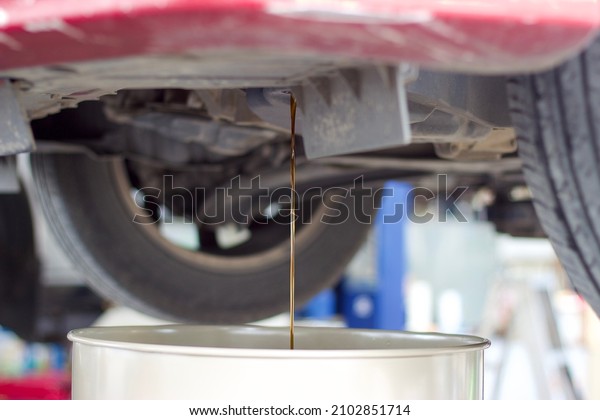 Transmission oil flowing down into container at\
the car maintenance garage in\
Thailand