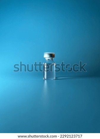 Transparent ampoule on a blue background. Contains medical supplies, drug, liquid or vaccine. One vial for medicine, aesthetic medicine treatment. Verticale
