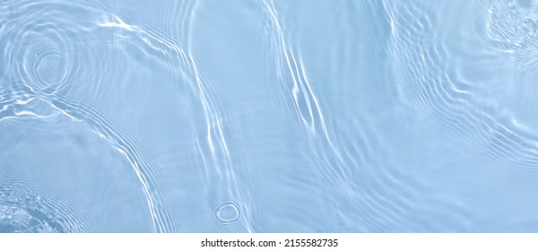 Transparent blue clear water surface texture with ripples, splashes. Abstract summer banner background Water waves in sunlight with copy space, top view. Cosmetic moisturizer micellar toner emulsion