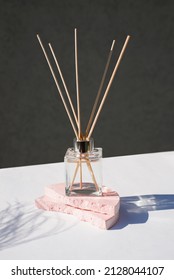 Transparent Bottle Of Aroma Diffuser On A Light Grey Background. Eau De Parfum For Home Presentation On A Podium With Plant Shadows . Trending Concept In Natural Materials.