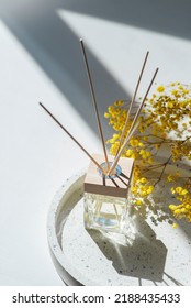 Transparent Bottle Of Aroma Diffuser On The Terazzo Podium On White Background. Eau De Parfum For Home Presentation On A Podium With Field Flowers. Trending Concept In Natural Materials.