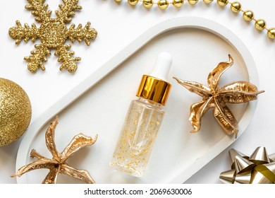 transparent bottle with beauty serum, hyaluronic acid, 24k gold and vitamins on a tray with new year decorations. Home face and body care concept