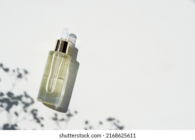 Transparent bottle with dropper pipette and serum or essential oil. White background with daylight and beautiful shadows. Skincare products, natural cosmetic. Beauty concept for face and body care - Shutterstock ID 2168625611