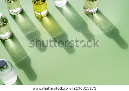 Transparent bottles of perfume on a green background. Natural light and shadows. Women's and men's essence concept, flatlay