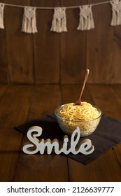 A transparent bowl of pasta with a wooden spoon inside on a wooden braun background with a white figurine Smile next to it. Spaghetti smash concept - Shutterstock ID 2126639777