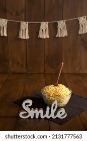 A transparent bowl of pasta with a wooden spoon inside on a wooden braun background with a white figurine Smile next to it. Spaghetti smash concept - Shutterstock ID 2131777563