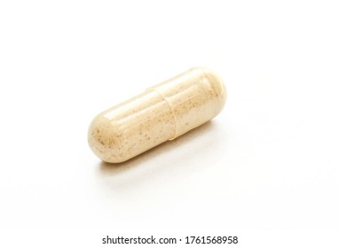 Transparent capsule filled with brown powder. Single pill isolated