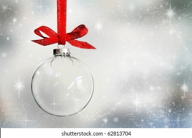 Transparent Christmas ball hanging on red ribbon on snowy winter background - Powered by Shutterstock