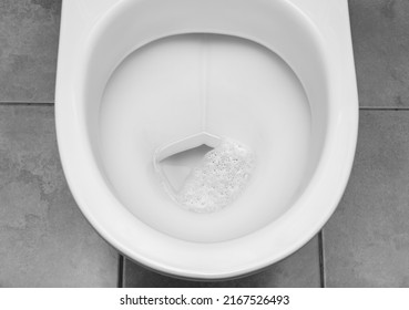 Transparent clean water with air bubbles in white toilet bowl. Focus at the center of image. Black and white image