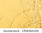 Transparent and clean yellow water background with sunlight reflection, top view