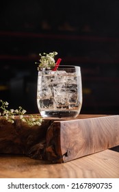 Transparent Cocktail With Ice And Gin And Tonic, Decorated With Flowers On A Dark Background. Bar Concept