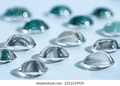 Transparent cosmetic drops of serum on a blue background, front view. Moisturizing gel against dry skin. - Shutterstock ID 2311219919