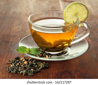 Transparent cup of green tea with lime on wooden background