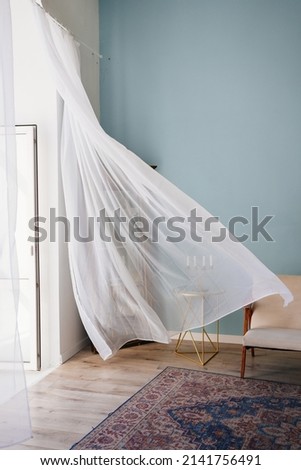 transparent fluttering curtain in the room with a candlestick on the table. romantic mood and spring weather. ventilation of premises. fresh wind.