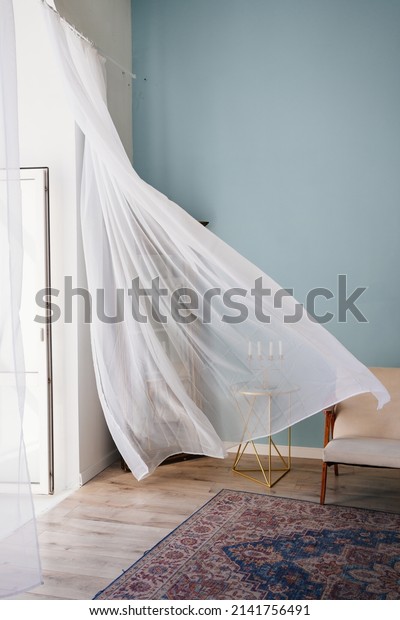 transparent fluttering curtain in the room with a\
candlestick on the table. romantic mood and spring weather.\
ventilation of premises. fresh\
wind.