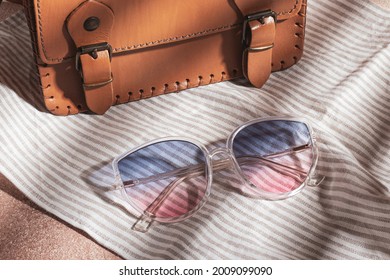 Transparent frame gradient sunglasses   brown leather bag are gray striped cotton fabric